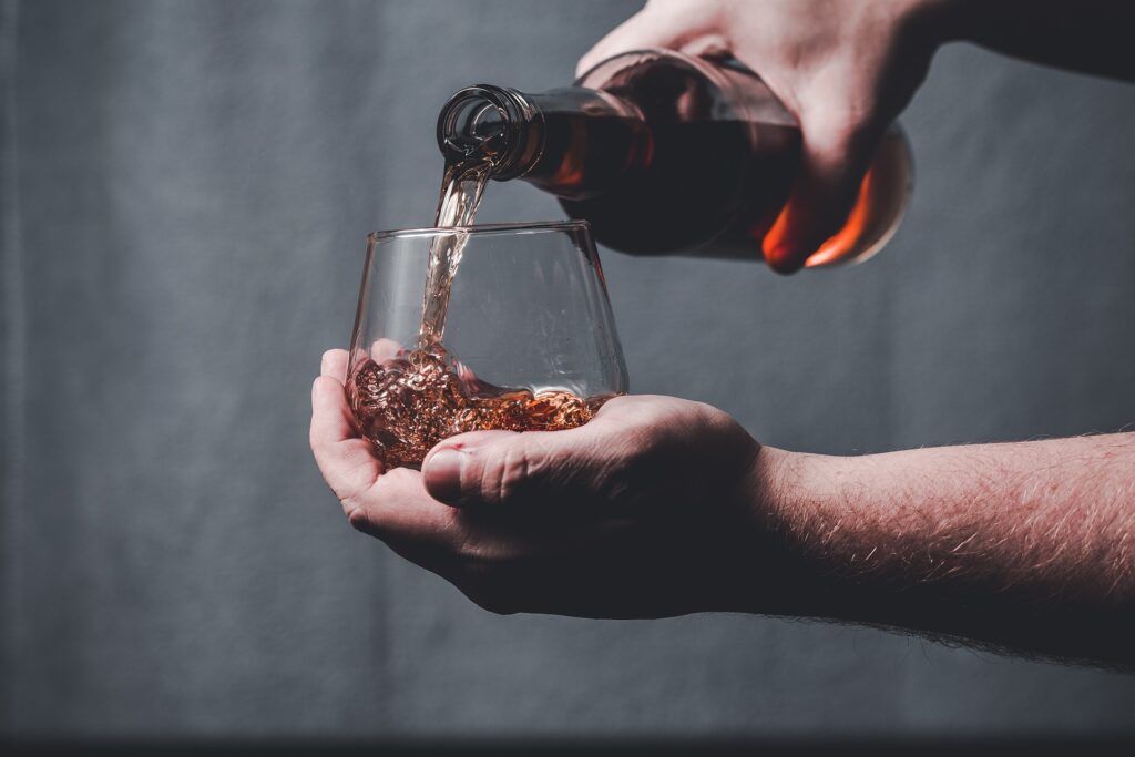 Brenner schenkt fertigen Whiskey in ein Glas