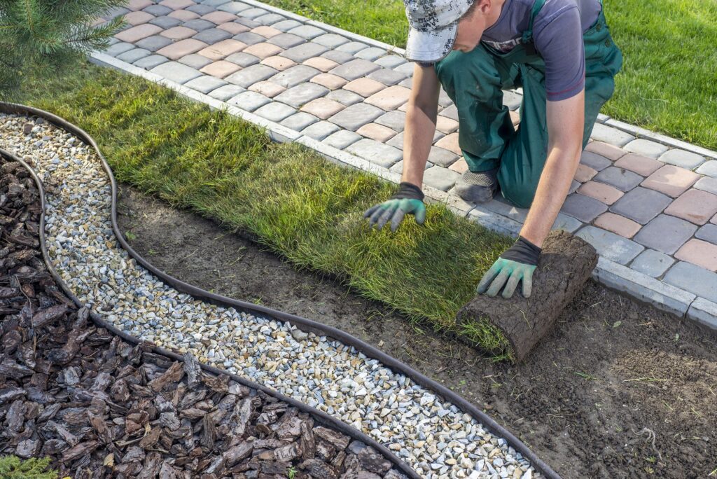 Garten- und Landschaftsbauer beim Verlegen von Rollrasen