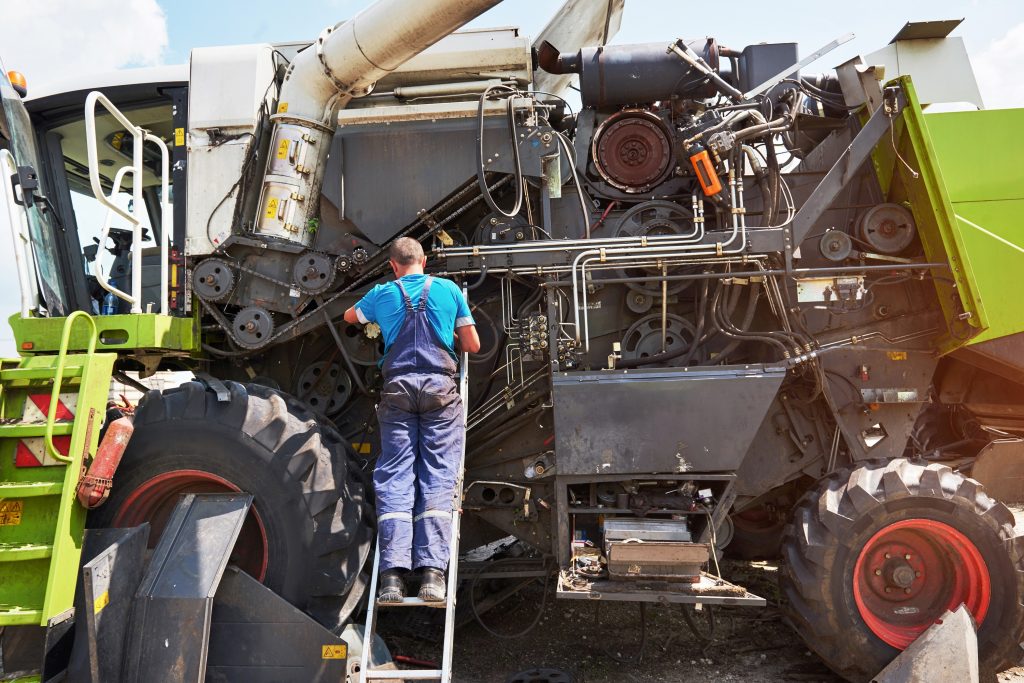 Land- und Baumaschinenmechatroniker bei der Wartung einer großen Landmaschine.