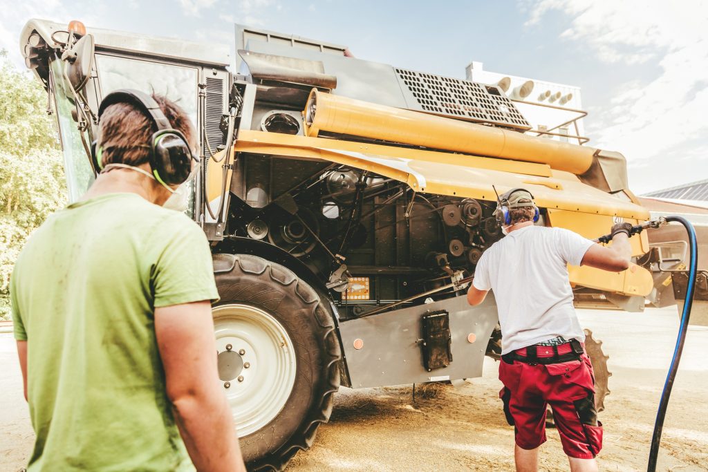 Land- und Baumaschinenmechatroniker bei der Reinigung einer großen Landmaschine.