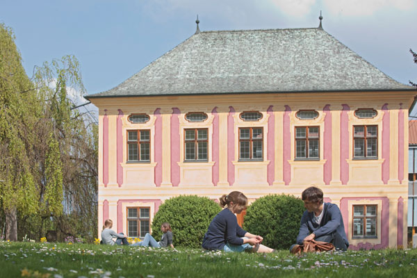 Studierende sitzen auf der Wiese vor der Hochschule Weihenstephan.