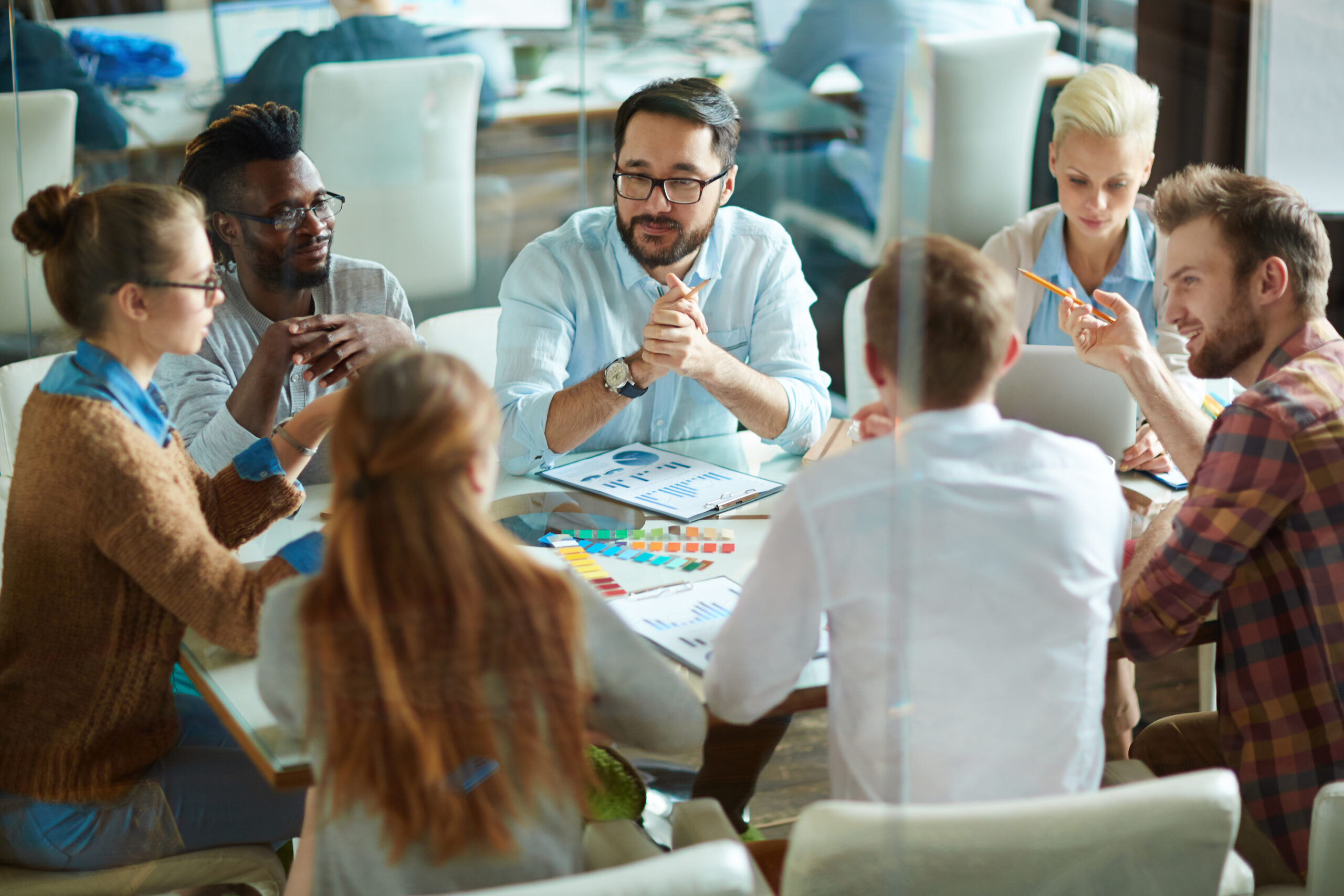 gruppenbesprechung: viele menschen sitzen an einem tisch und beraten und besprechen sich.