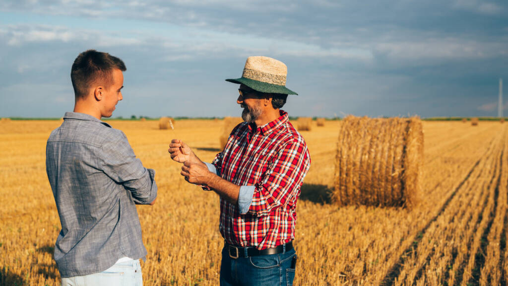 Zwei Männer sprechen an einem Getreidefeld