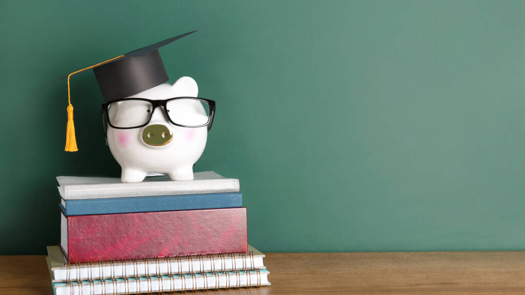 Sparschwein mit Doktorhut und Brille auf Büchern